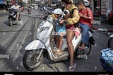 This biker is pausing before pulling into traffic from a soi.