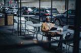 A man sitting in a chair with folder in his hand and laptop on the table.