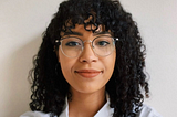 Woman with glasses and curly hair smiles