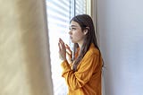 Anxious young woman looking out of the window.