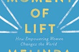 A photo of a book called The Moment of Lift: How Empowering Women Changes the World by Melinda Gates. The cover has a blue background with yellow and white writing and three white streaks on each side of word lift.