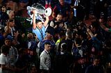 Rodri lifting the UCL trophy, surrounded by photographers.