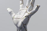 Picture of a white statue of a hand that has repaired from a previous shattering and looking beautiful with the cracks fixed with gold, representing the concept that things can look more beautiful after be repaired than they were before they broke.
