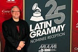 Jamie Ousley poses in front of a sign that says “Latin Grammy Nominee Reception”