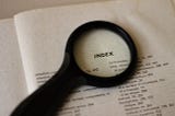 A photo of a magnifying glass over the index page of a book.