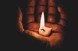 Hand holding candle in the dark