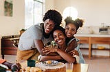 A family shares a joyful breakfast together, with kids hugging and appreciating their loving mom.