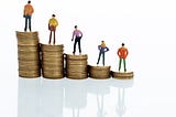 Figurines standing on stack of coins