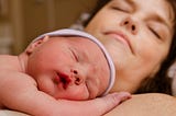 An infant sleeping on his mother’s chest.