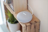 Google Home Mini, sitting on shelf. Harlow Journey Article about Google Home Please Don’t Talk to Me That Way!