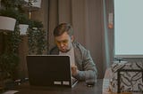 Man thinking hard while typing out his wife’s reviews on the computer.
