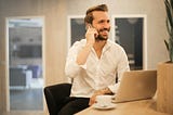 A businessman in business attire busily takes a phone call.