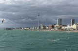 View of British seaside from far out in the choppy, green water under a bruised, gray sky