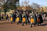 Pipers in saffron kilts marching while playing the bagpipes