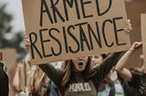 AI-generated picture of student holding a non-peaceful violent sign calling for “armed resistance”