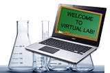 A laptop with a blackboard on the screen and lab glassware in background
