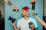 Man with red beanie can’t decide what camera to use