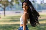 A woman in a white top crop is smiling while looking at the camera. Photo by Jeff Denlea from Pexels.