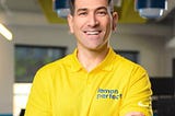 A headshot of Yanni Hufnagel in a yellow shirt that says “Lemon Perfect”