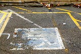 Imagem de vaga de estacionamento reservada para pessoa com cadeira de rodas. A pintura do simbolo da cadeira de rodas está desgastada.