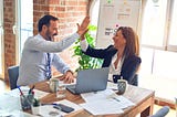 Man and woman high-fiving at a table.