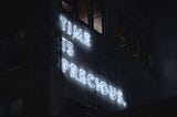 neon text on a building saying time is precious