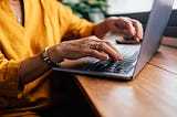 Closeup of an older woman’s hands on her laptop keyboard.