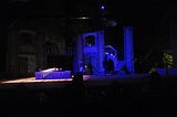 The set for the Capulet tomb in a stage production of Romeo and Juliet, with Juliet on the tomb, Romeo looking on.