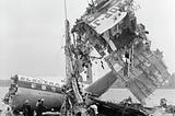 wreckage of crashed passenger airplane lifted by crane onto barge