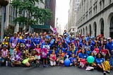Large group of people holding up Pride signs and wearing NYC Human Rights shirts