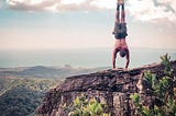 How to instantly improve your handstand header image. The author doing a handstand on the edge of a cliff in Krabi, Thailand.