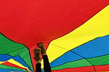Colourful parachute , red, yellow, blue and green with 2 feet pressed up in the air against it