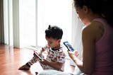 Mom and young son on phone and tablet.