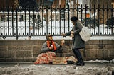 A women giving donating to a homeless man.