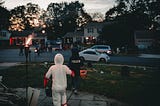 two children running in their neighborhood, on Halloween