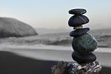Grey pebbles stacked on top of each other with grey toned beach scene behind