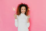 Woman in White Turtleneck Sweater Holding Pink Lighted Sparkler
