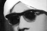 Black and white photo of Mahmoud Falah, a handsome young man in white turban and dark sunglasses.