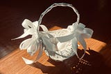 White basket with white ribbons with two white chicken eggs inside