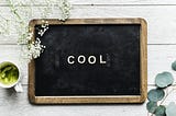 A small aesthetically designed blackboard with the words “cool” written in chalk