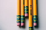 Several pencils on the edge of a white table.