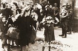 A roup of Polish Jews captured by German soldiers during the suppression of the Warsaw Ghetto Uprising (Poland). Some are women with raised hands. One is a little boy, also with hands raised.