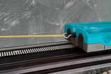 the image shows a vernier go direct cart on a track. on the side of the cart, a rubber band is hooked and stretched.
