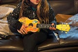 My granddaughter Charlotte with a Yellow Submarine ukulele I sent to my grandkids. Photo taken by Erika Milienz.