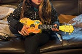 My granddaughter Charlotte with a Yellow Submarine ukulele I sent to my grandkids. Photo taken by Erika Milienz.