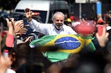 The newly elected president, Luís Inacio “Lula” da Silva, holding the brazilian flag and waving to a crowd.