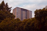 Photo of green trees near white concrete tower block building during daytime