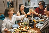 Four people toasting at the dining table.
