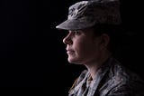 Profile of a female soldier looking pensive with a dark background