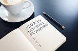 A black notebook with 2023 New Year’s Resolutions written in it in pencil.